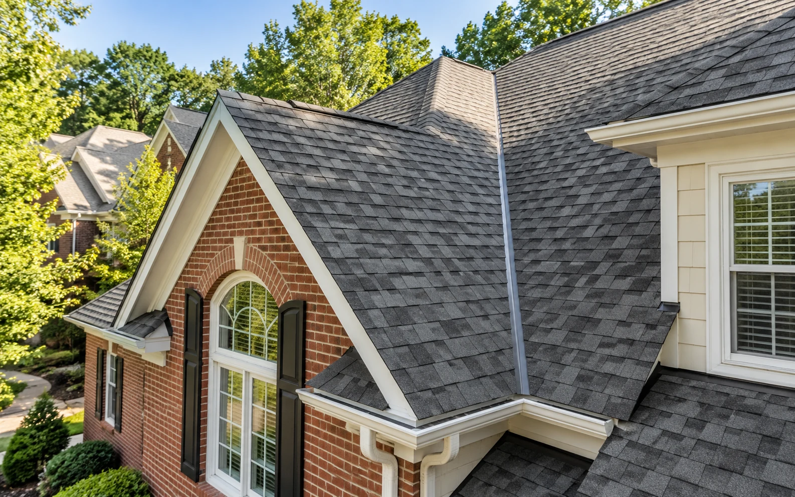 Intersecting shingle rooflines above brick and siding