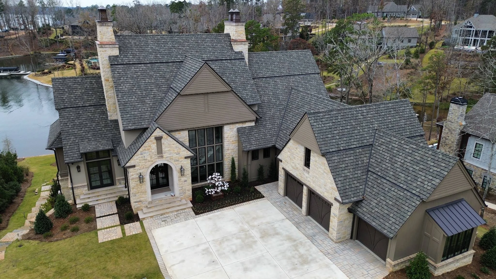 Drone photograph of a gray shingle roof on a stone-front home